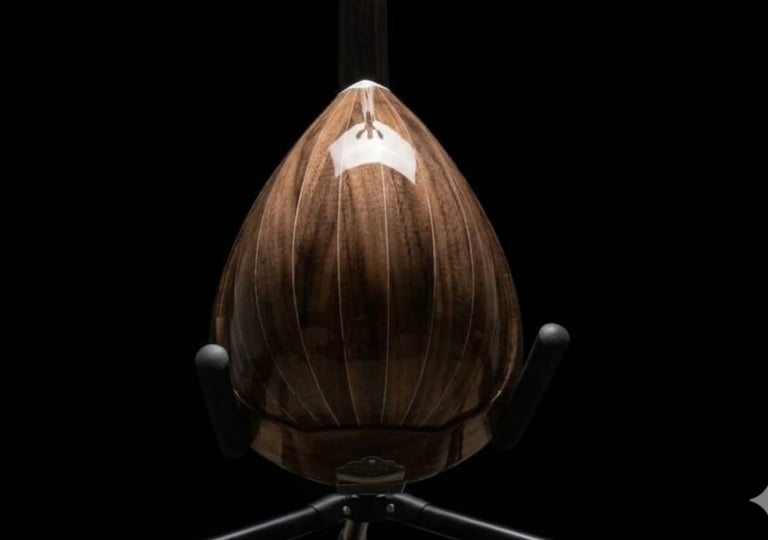 Brown wooden pendant light with vertical ridged design and illuminated top, suspended against black background