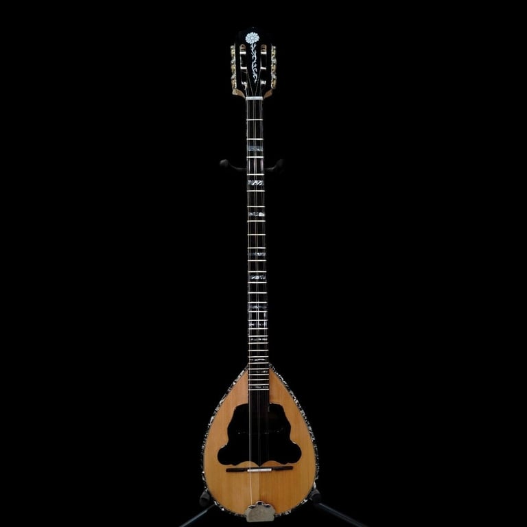 A wooden bouzouki with a pear-shaped body and fretted neck positioned against a black background.