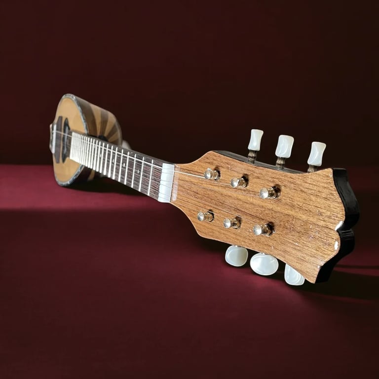Wooden ukulele with white tuning pegs displayed at an angle against a dark red background