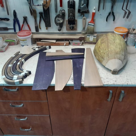 Upholstery workshop with fabric swatches, tools on pegboard wall, and materials on wooden workbench