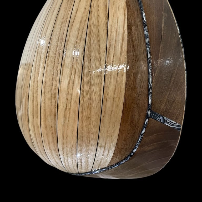 Wooden basket or woven vessel with vertical slats and dark braided handles against black background