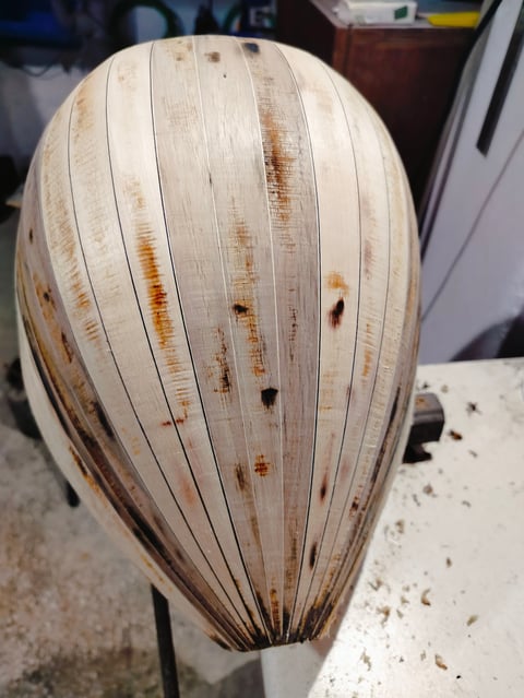 Dried onion papery skin with vertical ridges and brown rust-colored stains, displaying natural aging and weathering patterns.