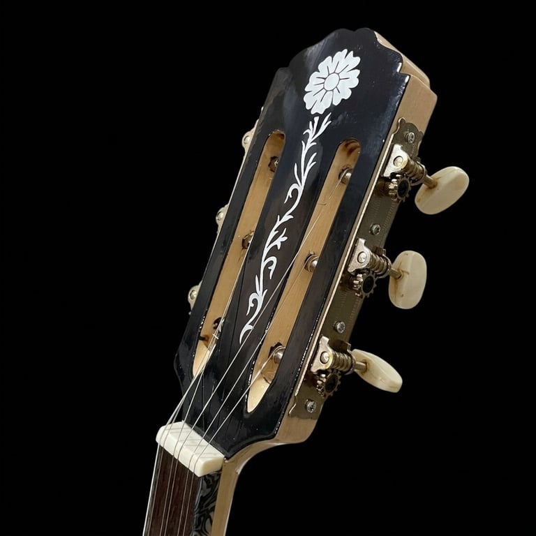 Headstock of an acoustic guitar with black finish, white floral inlay, and tuning pegs against black background