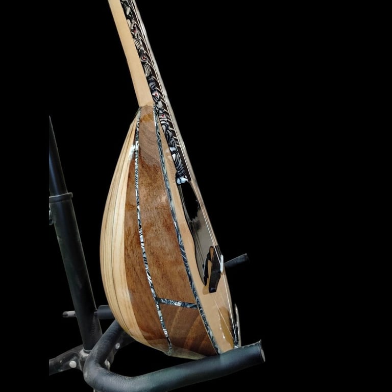 Side view of an oud musical instrument with wooden body and ornate inlays displayed on a stand against a black background