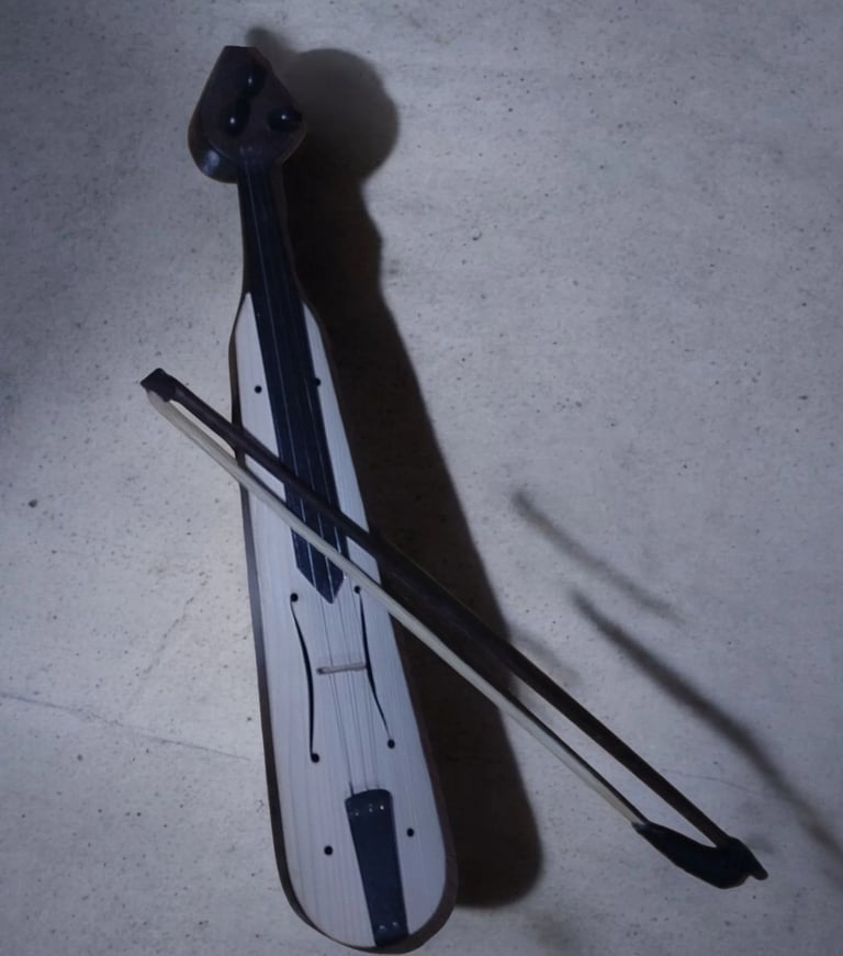 Electric violin with bow on concrete surface, casting a distinct shadow