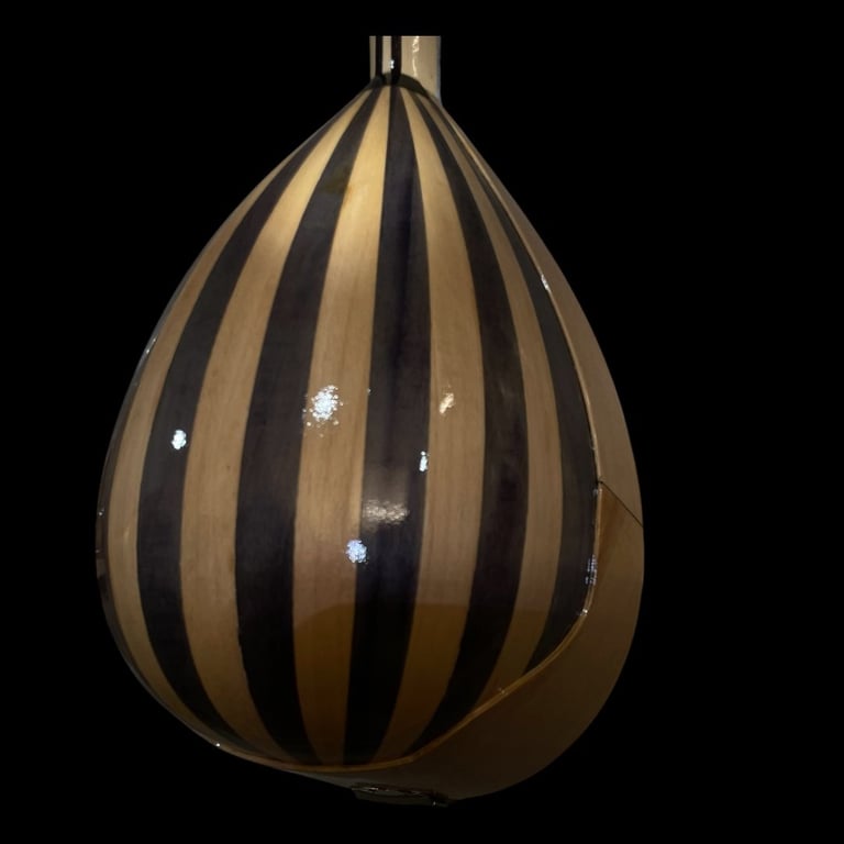 Teardrop-shaped pendant lamp with alternating tan and black vertical stripes on black background