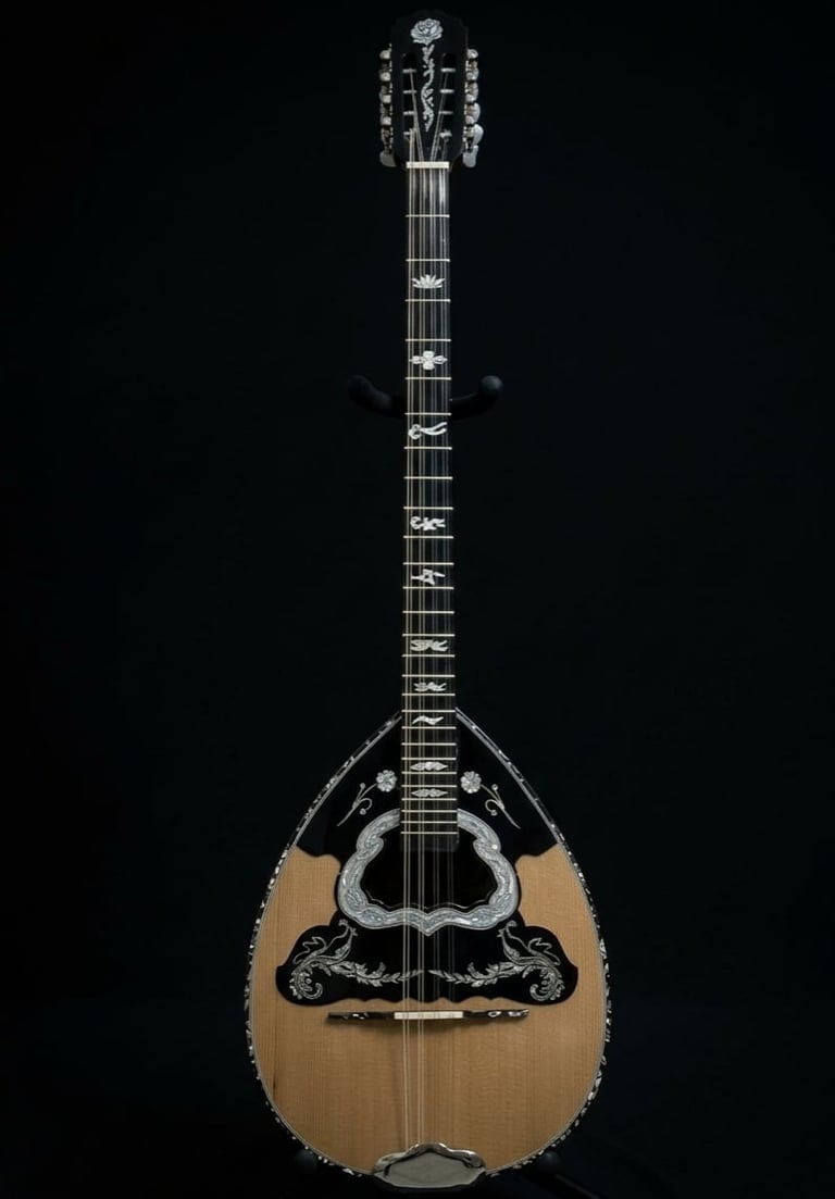 Greek bouzouki with wooden body, long neck, and ornate black inlay on black background