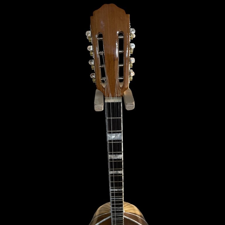 Back view of a classical guitar with nylon strings, wooden body, and dark fretboard against black background