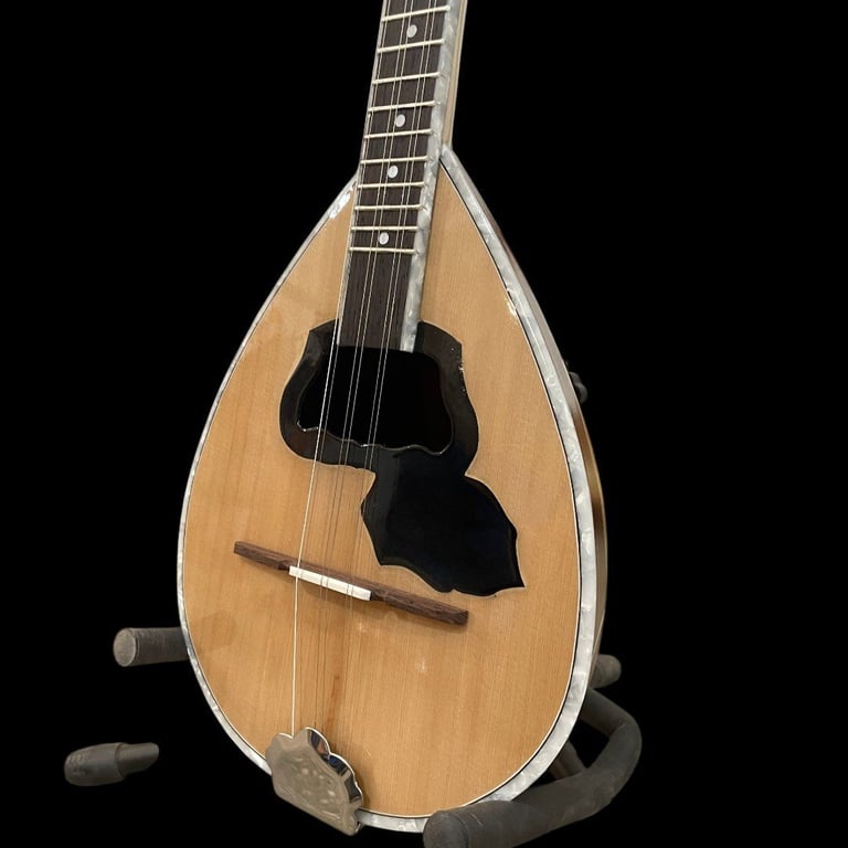Wooden mandolin with teardrop-shaped body, dark pickguard, and fretted neck against black background